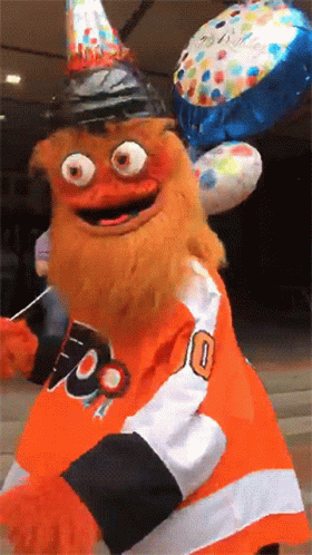 Gritty holding a birthday balloon, wearing a party hat, and blowing a kiss toward the camera.