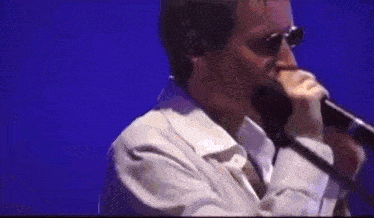 a man wearing glasses is singing into a microphone