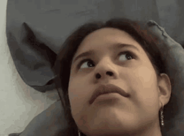 a young girl is laying on a bed and looking up at the camera .