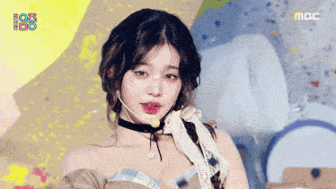 a woman wearing a choker and a microphone on a stage with the letters mbc on the bottom right
