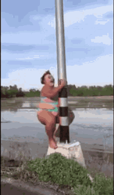 a woman in a bikini is standing on a pole in the water .