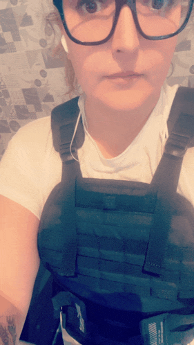 a woman wearing glasses and a black vest that says tactical on it