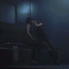 a woman in a black dress is sitting in a dark room with a microphone in her hand .