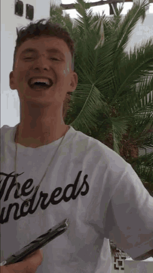 a man wearing a white shirt that says the reds on it is laughing