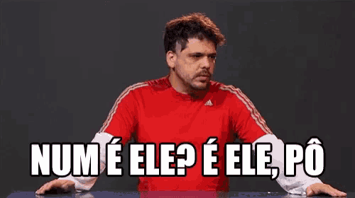 a man in a red adidas shirt is sitting at a table and says num e ele ? e ele po