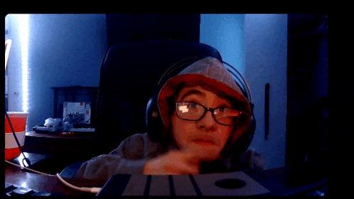 a person wearing headphones and glasses is sitting in front of a laptop