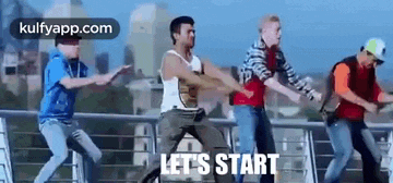 a group of men are dancing on a bridge and the words `` let 's start '' are visible .