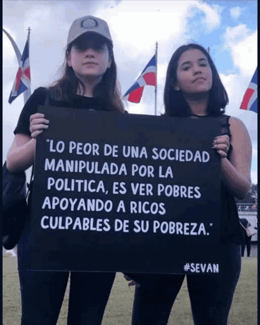two women holding a black sign that says " lo peor de una sociedad manipulada por la politica