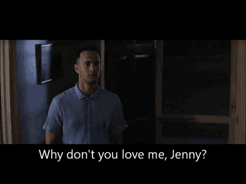 a man in a blue shirt stands in a dark room and says " why don 't you love me jenny "