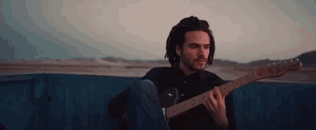 a man with dreadlocks is playing an electric guitar in a truck .