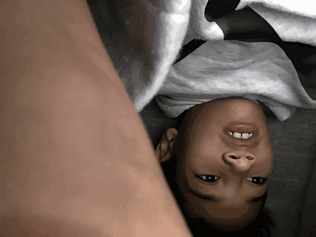 a child laying upside down with a white towel on his head