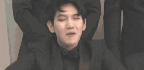 a man in a suit and bow tie is making a funny face with his hands .