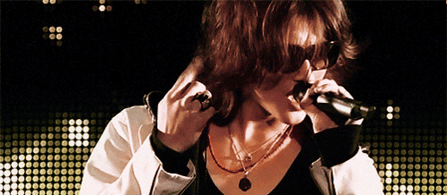 a woman singing into a microphone in front of a polka dot background
