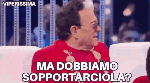a man in a red sweater is sitting in a chair and says ma dobbiamo supportarciola ?