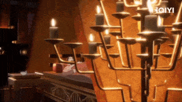 a woman is sleeping on a bed in a room with candles and a chandelier .