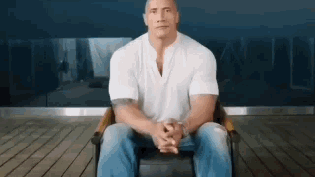 a man is sitting in a chair with his hands folded and looking at the camera .