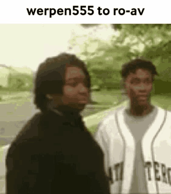 two men are standing next to each other on a sidewalk and talking to each other .