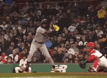 a baseball player is swinging at a pitch while a crowd watches