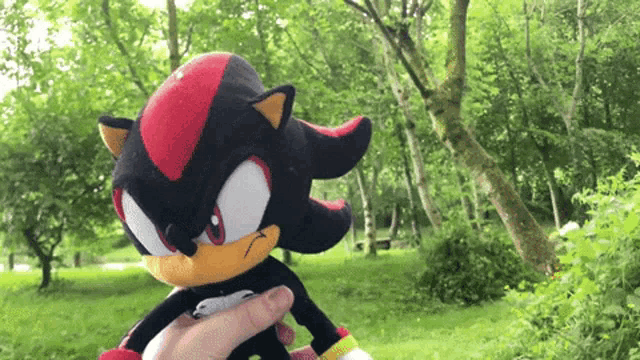 a person is holding a stuffed animal that looks like shadow the hedgehog .