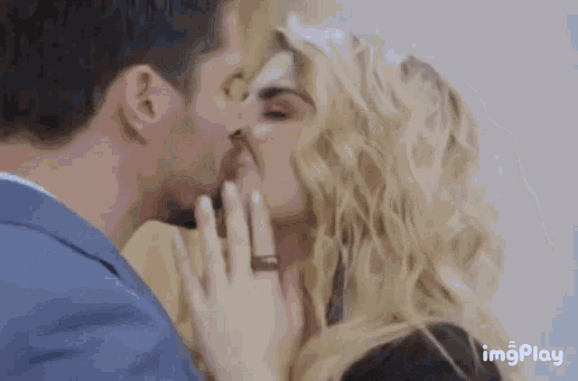 a man and a woman are kissing with a ring on her finger .