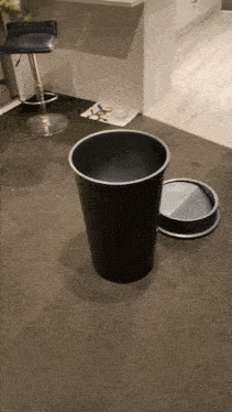 a black trash can is sitting on a carpeted floor