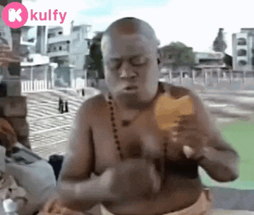 a shirtless man is eating an ice cream cone with a kulfy logo in the corner