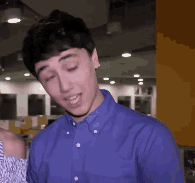a man in a blue shirt is making a funny face