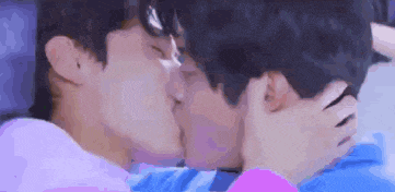 a couple of young men are kissing each other on the cheek .