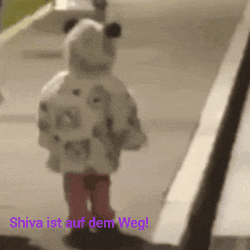 a little girl is walking down a sidewalk with the words " shiva ist auf dem weg " above her