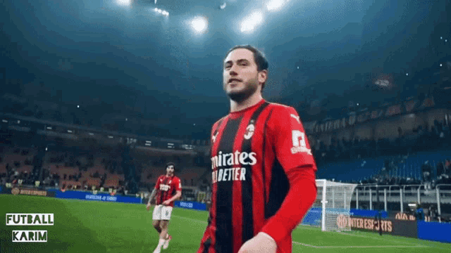 a soccer player wearing a red and black jersey that says " mirates fly better "