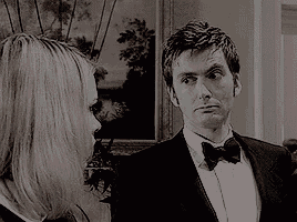 a man in a suit and bow tie is standing next to a woman in a black and white photo .