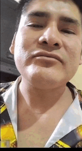 a close up of a man 's face with a yellow and black shirt on