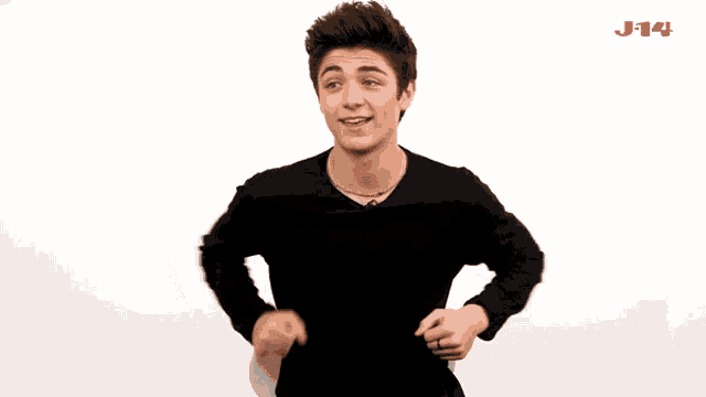 a young man in a black shirt is dancing in front of a white background with the letters j14 visible