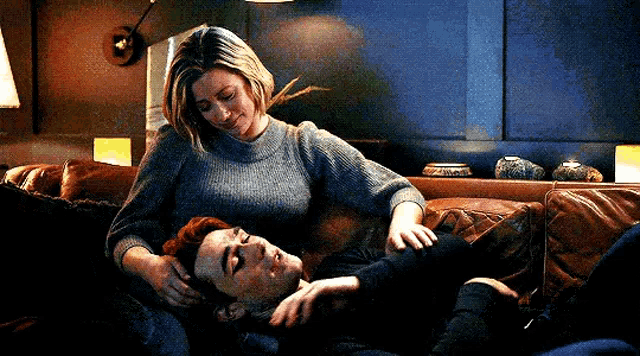 a man and a woman are laying on a couch together .