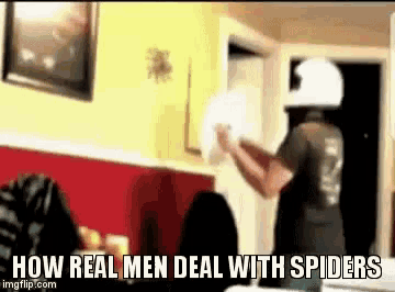 a man in a white helmet is holding a spider in his hand with the words how real men deal with spiders below him