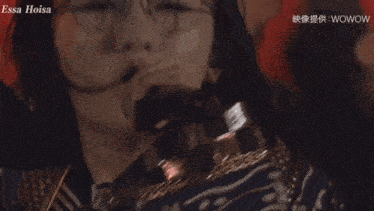 a woman singing into a microphone with the words essa hoisa on the bottom right