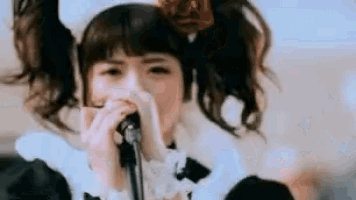 a young girl is singing into a microphone while wearing a maid outfit .