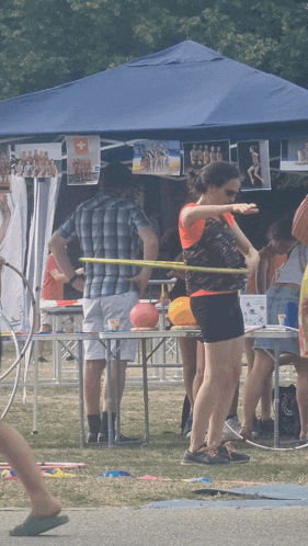 a group of people are playing hula hoops in front of a tent