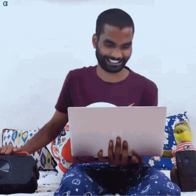 a man sitting on a bed using a laptop computer
