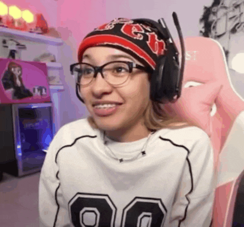 a woman wearing glasses and headphones is sitting in a pink chair in a room .