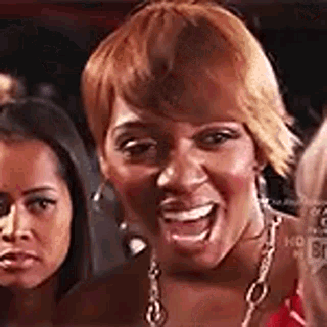 a group of women are standing next to each other in a room and one of them is smiling .