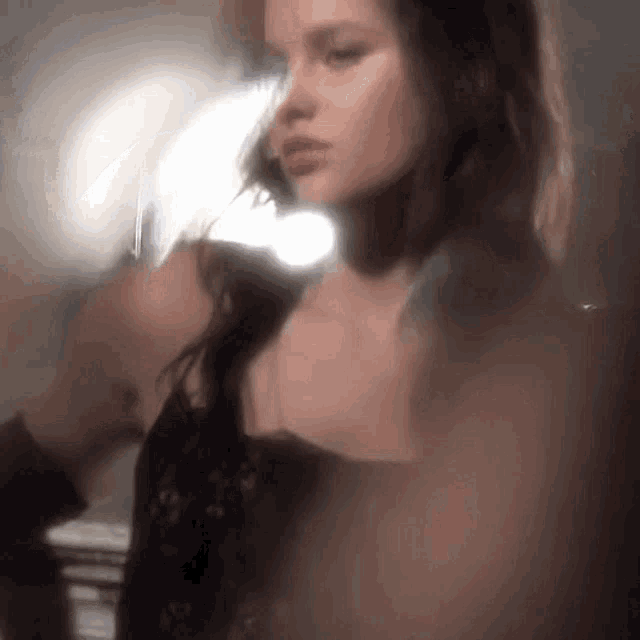 a woman in a black dress is standing in front of a mirror in a room .