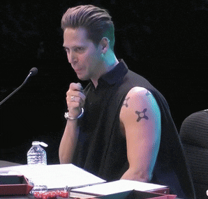 a man with a tattoo on his arm sits at a desk