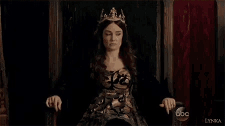 a woman is sitting on a throne wearing a crown and a dress .