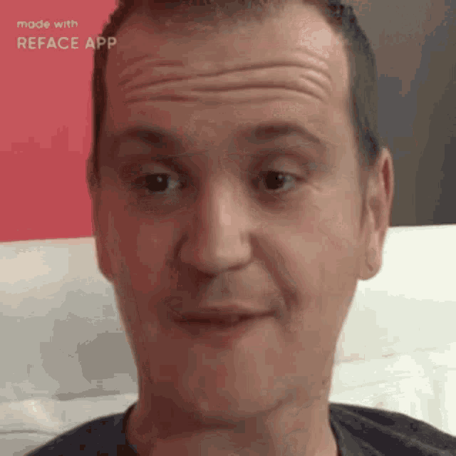 a man is making a funny face with his tongue out while sitting on a bed .