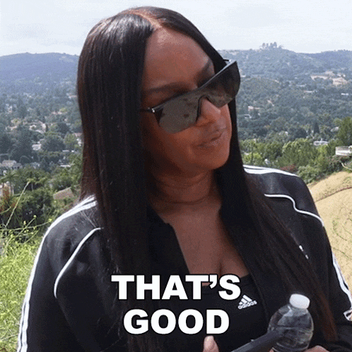 a woman wearing sunglasses says that 's good while holding a bottle of water