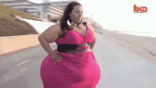 a woman in a pink dress is walking down a street with a btv logo in the corner