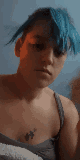 a woman with blue hair has a small puzzle piece tattoo on her chest