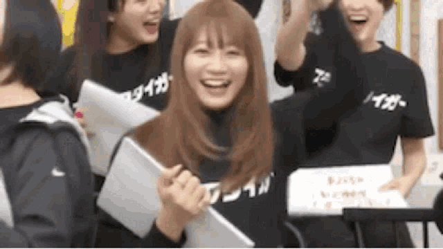 a group of young women are standing next to each other and laughing while holding papers .