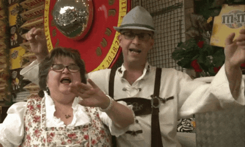 a man and a woman are posing for a picture in front of a sign that says ' m & m '